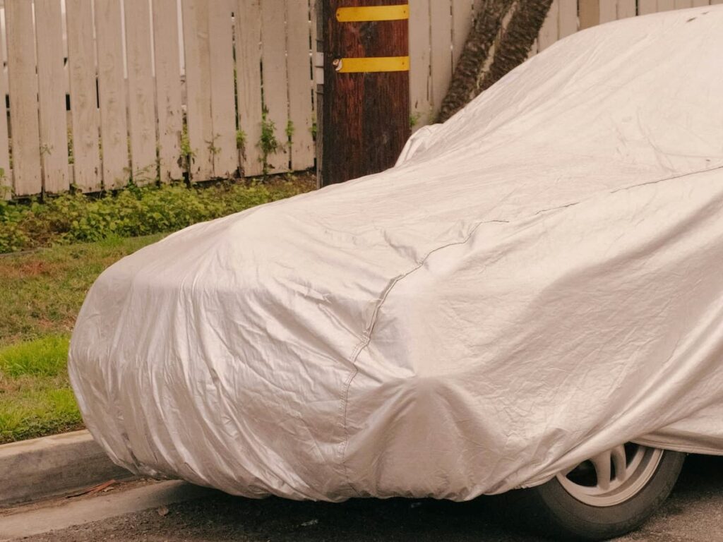 a car outside on the street covered with a car cover