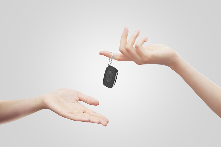 a woman handing over the keys to a refinanced car to a man
