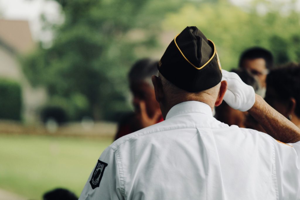 a veteran salutes a group of people outside