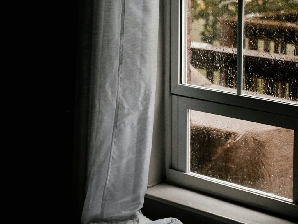a dark room with rain on the windows to symbolize depression