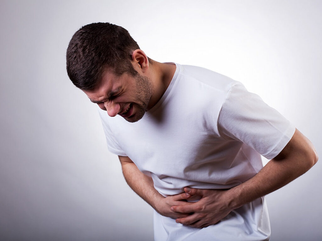 a man holds the side of his stomach in pain from ibs