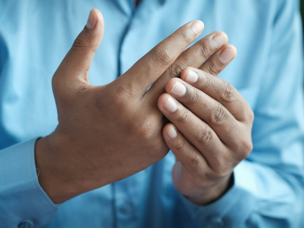a man rubs his hands because of rheumatoid arthritis