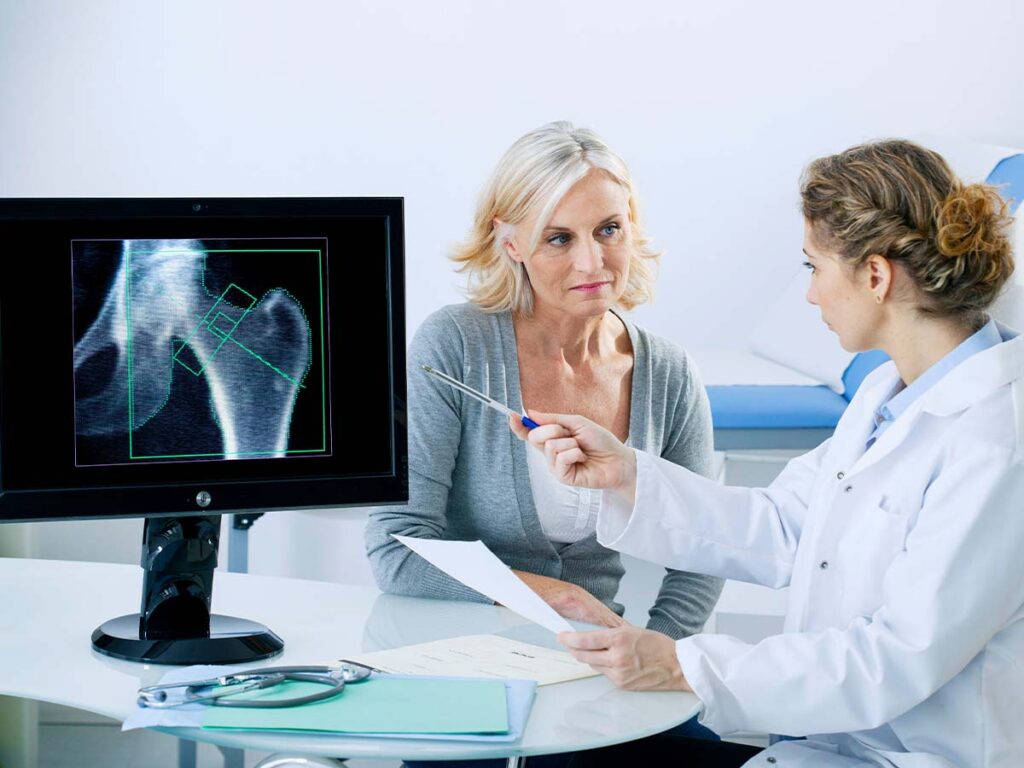 a doctor shows an xray of hip bones to a patient to discuss osteoporosis