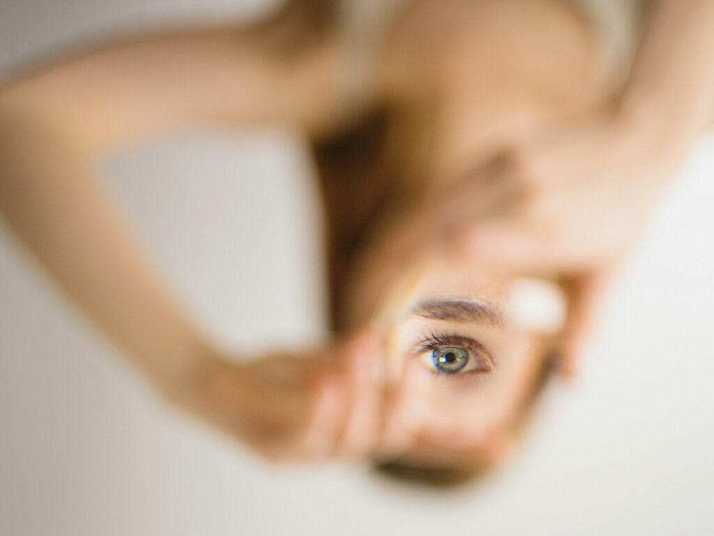 a woman looks at her eye in a mirror to symbolize Histrionic Personality Disorder