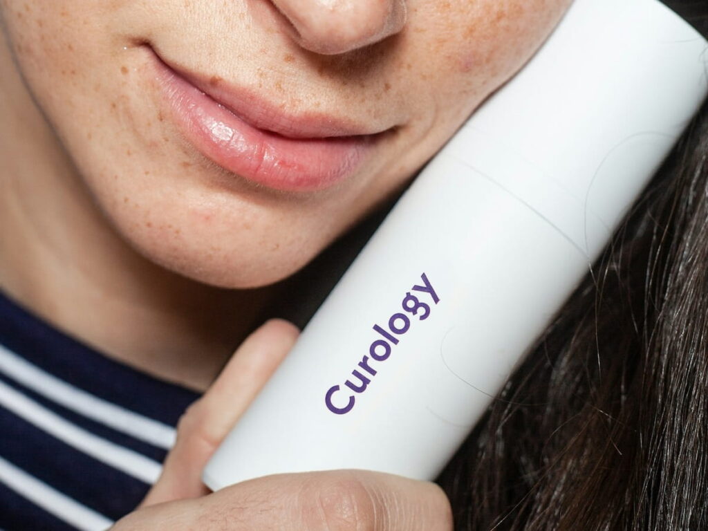 a young woman holding a bottle of acne cleanser