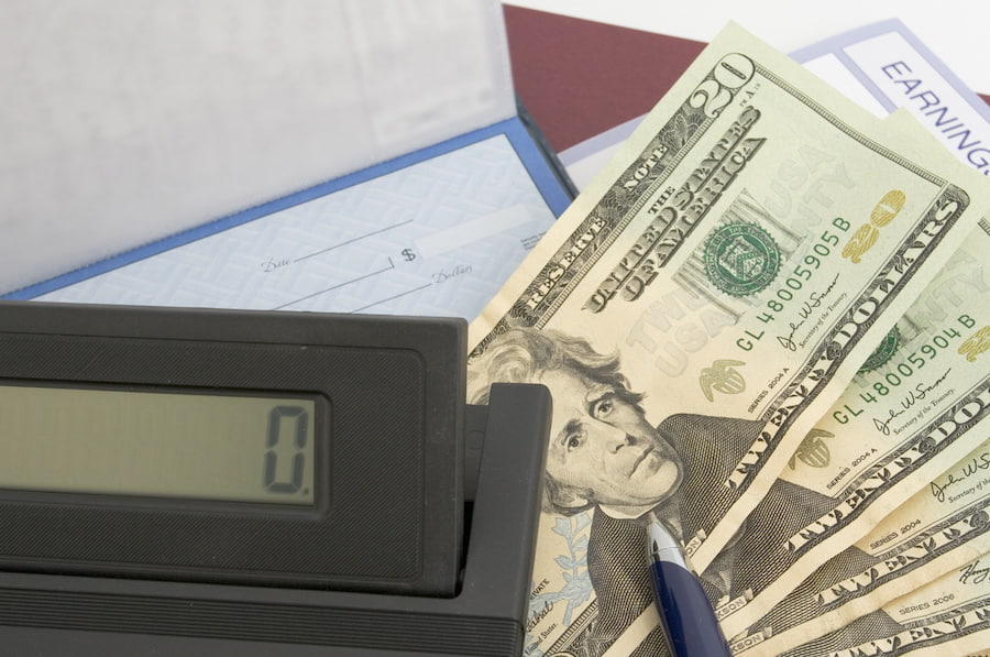 twenty dollar bills next to a calculator on top of a messy work desk