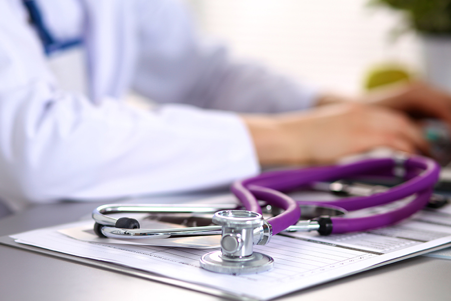 a doctor with a stethoscope and clipboard writes a diagnosis of fibromyalgia