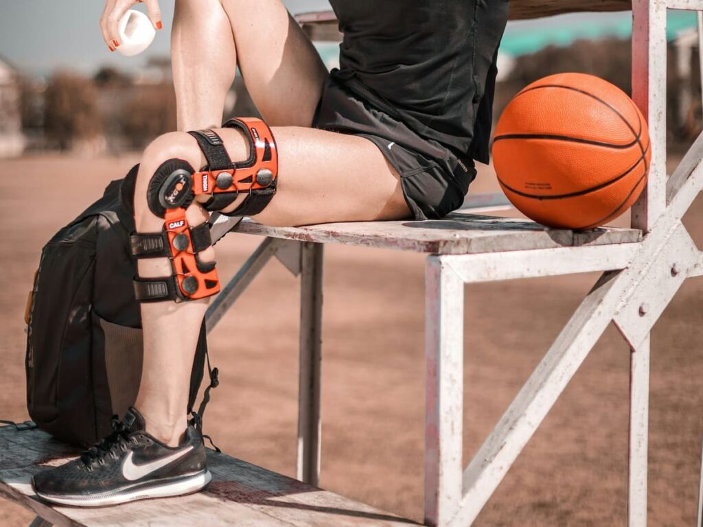 a woman taking a break from playing basketball with a brace on her knee