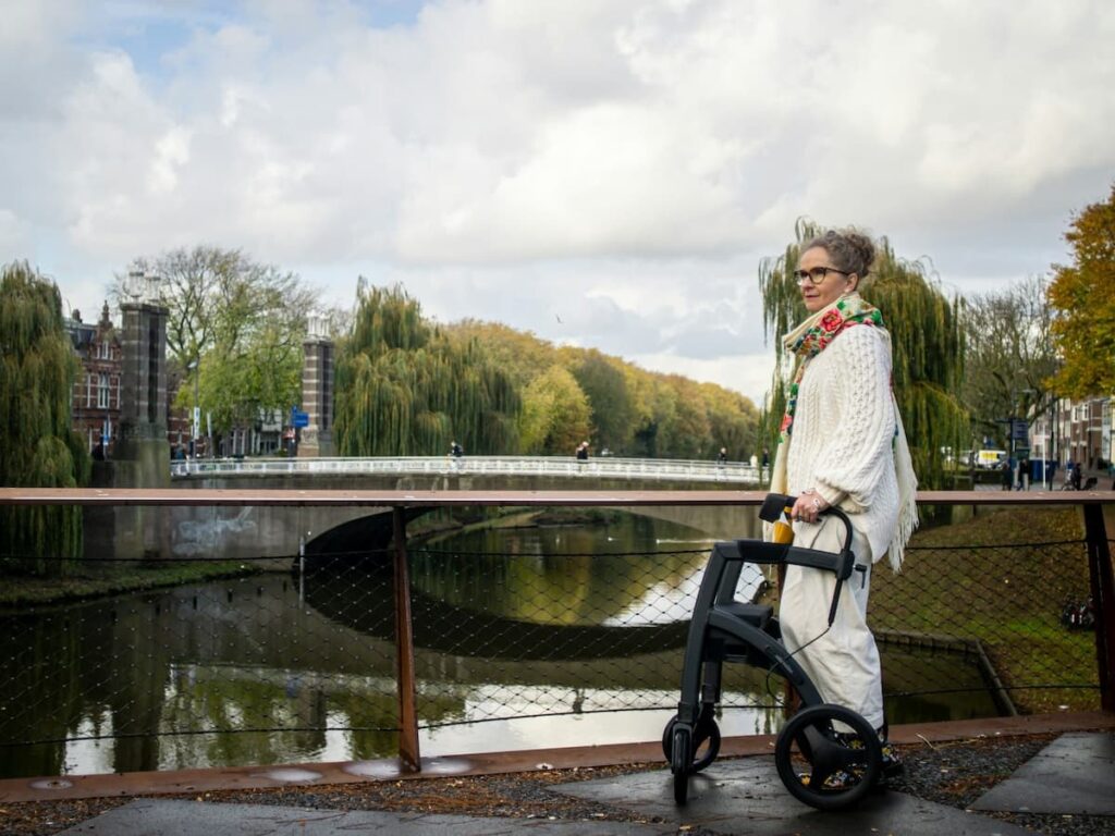 a woman who is a parkinson's disease patient walking outdoors with her mobility walker