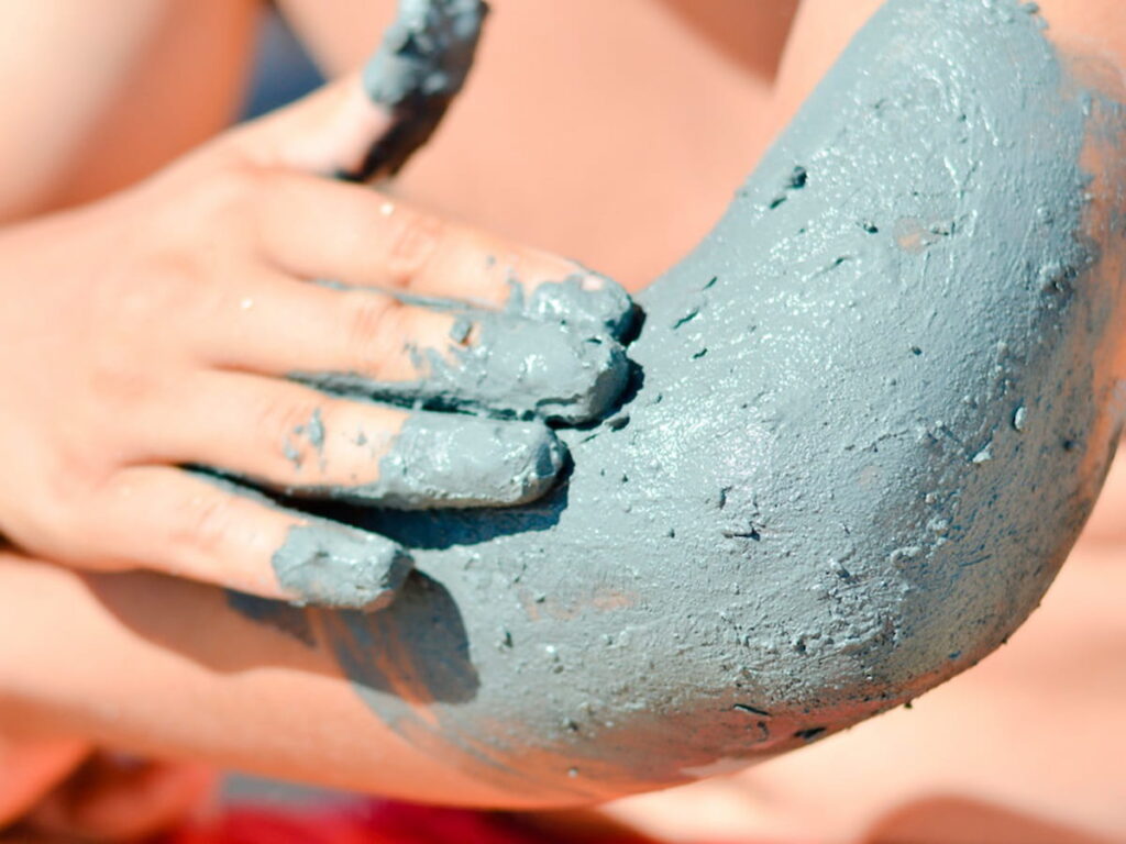 rubbing a mud mask on an elbow to resolve psoriasis
