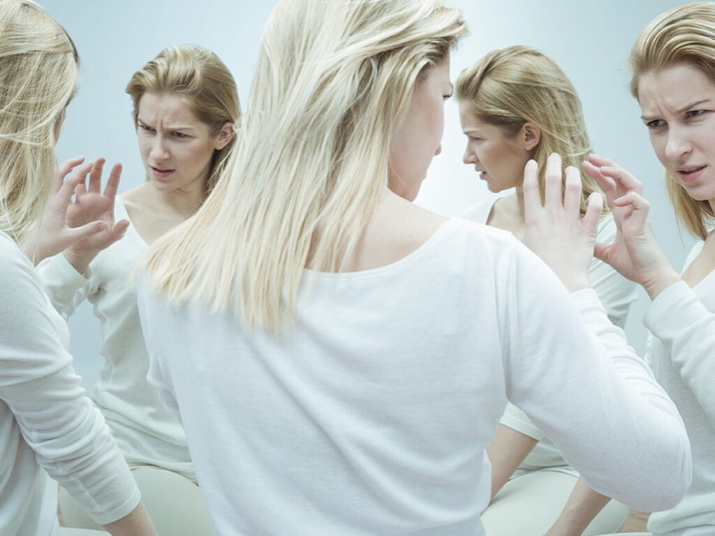 a woman looks at various versions of herself to symbolize schizophrenia