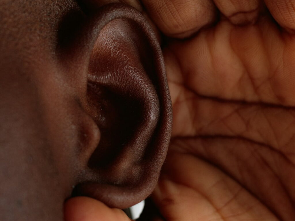a man cups his hand around his ear because of tinnitus