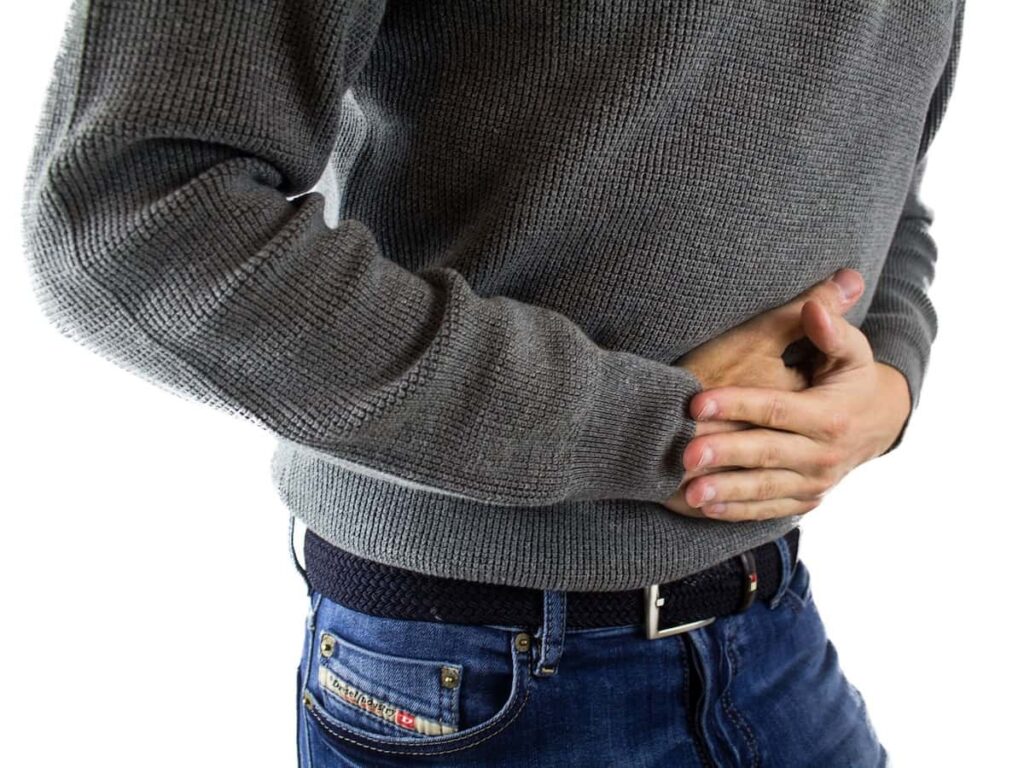 a man grabs his stomach in pain because of ulcerative colitis