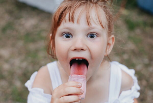 a little girl eating candy out of a container turning her tongue red
