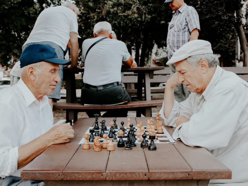 two older men play chess in an outdoor public park