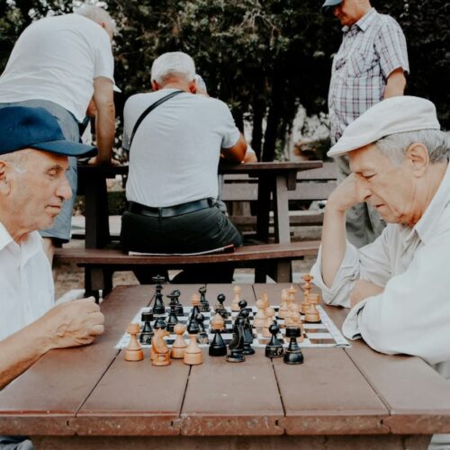 two older men play chess in an outdoor public park