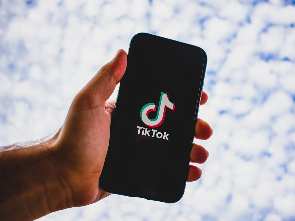 a man holding a phone with the tiktok logo on it