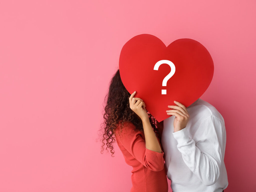 a man and woman holding a heart with a question mark on it.