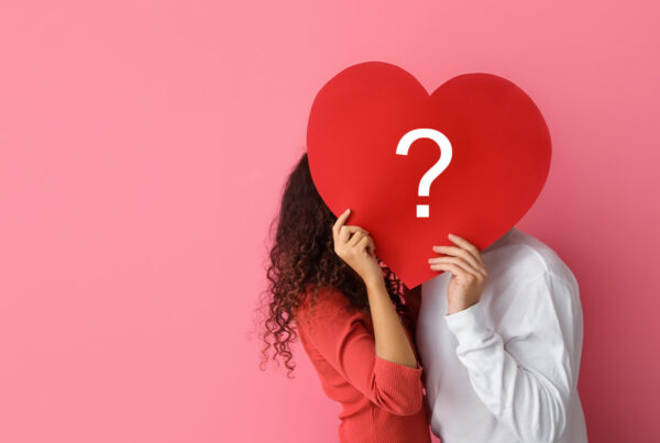 a man and woman holding a heart with a question mark on it.