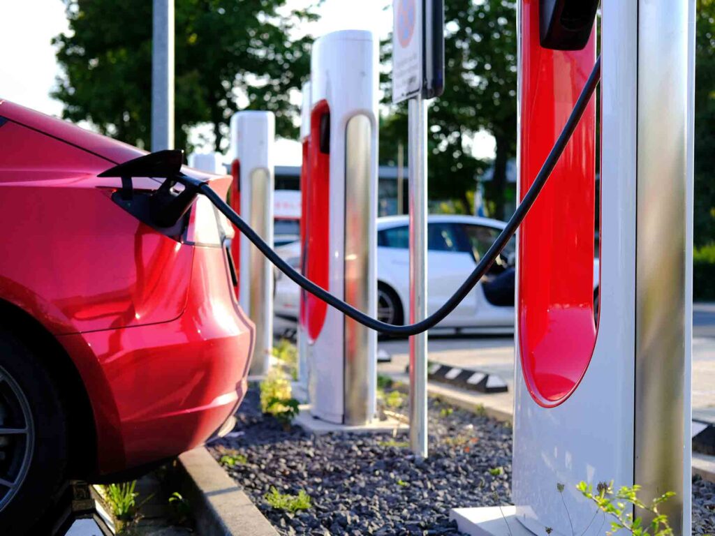 a red Tesla car charging at an electric vehicle charging station