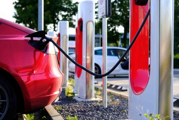 a red Tesla car charging at an electric vehicle charging station